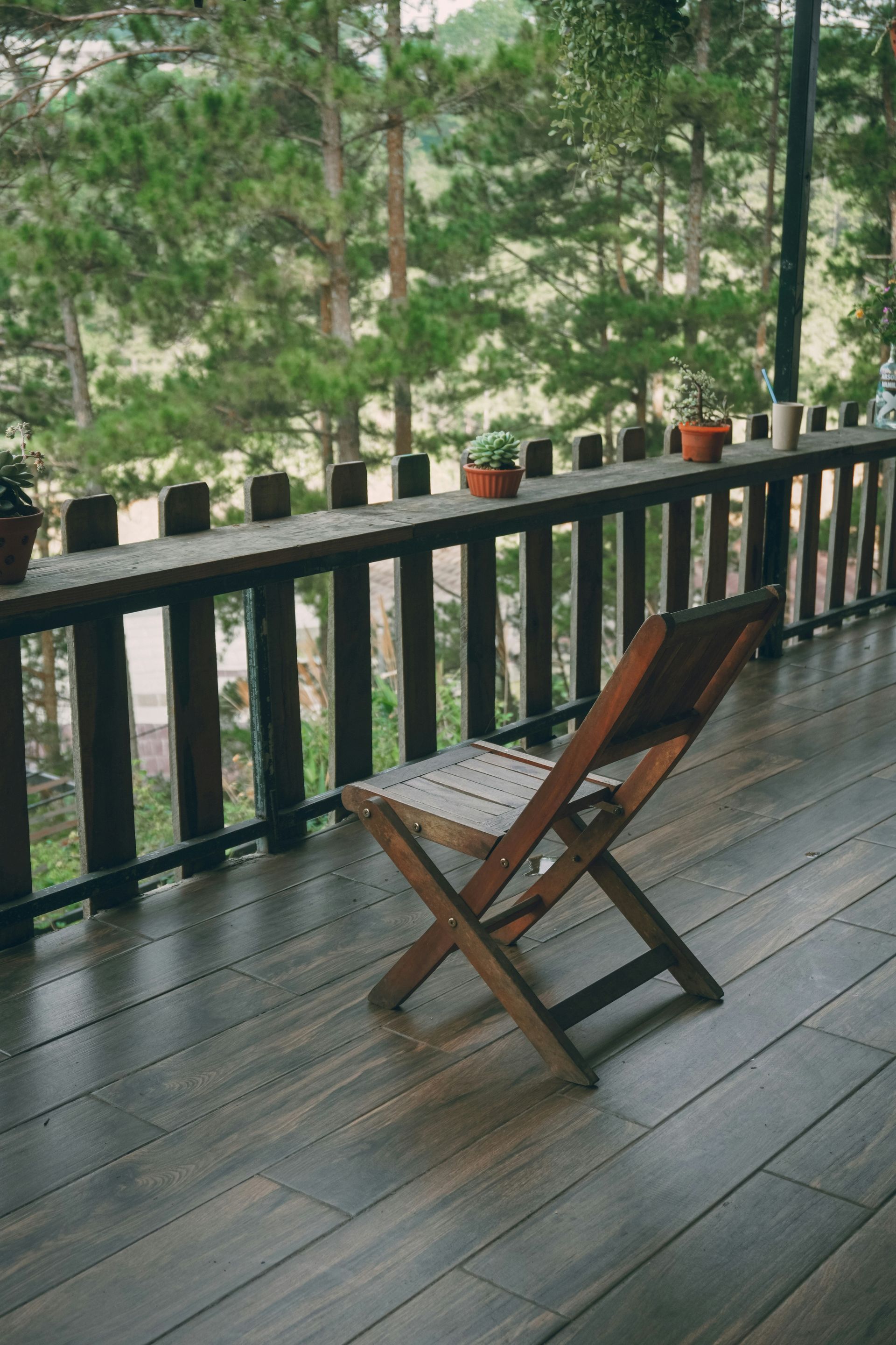 A wooden chair on a deck overlooking a forest